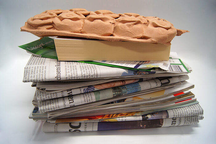 Stapel Altpapier aus Zeitungen, einem Buch und einem Eierkarton