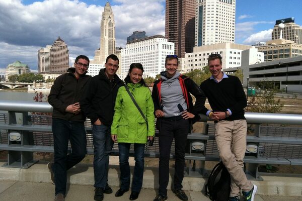 4 Männer und 1 Frau stehen auf einer Brücke vor der Skyline von Columbus