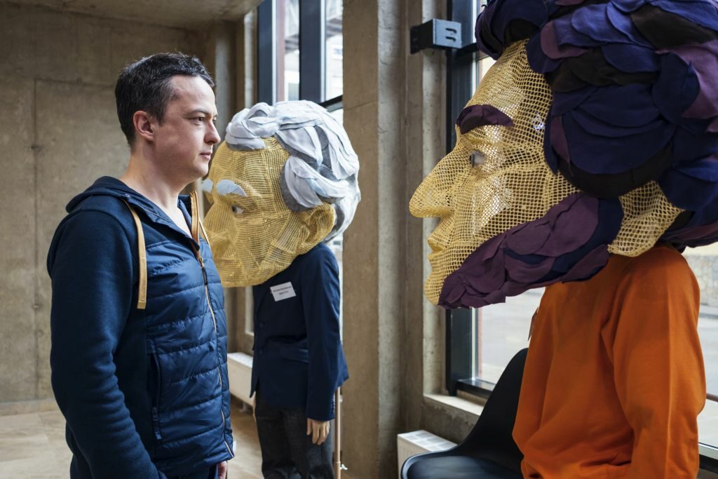 Ein Ausstellungsbesucher betrachtet mannshohe Puppen, die berühmte Sachsen darstellen