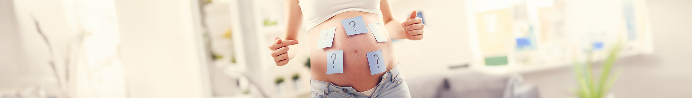 Foto von einer schwangeren Frau mit Fragezeichen auf dem Bauch