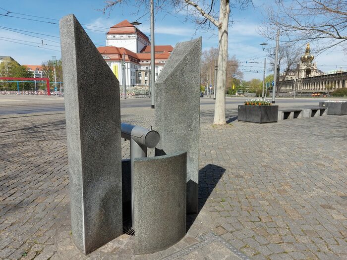 Trinkwasserbrunnen Postplatz: eckige und runde Elemente aus Granit umschließen den Brunnen. Das Wasser fließt in ein Gitter am Boden ab.