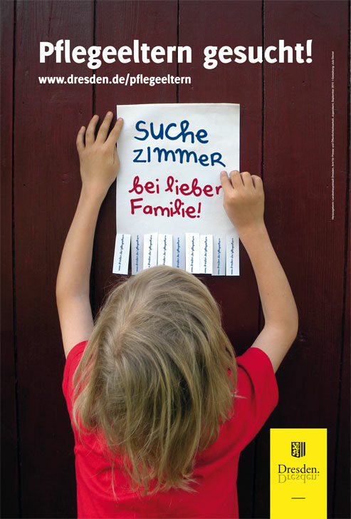 Ein Kind befestigt einen Zettel an einer Wand. Auf dem Zettel steht: Suche Zimmer in lieber Familie!