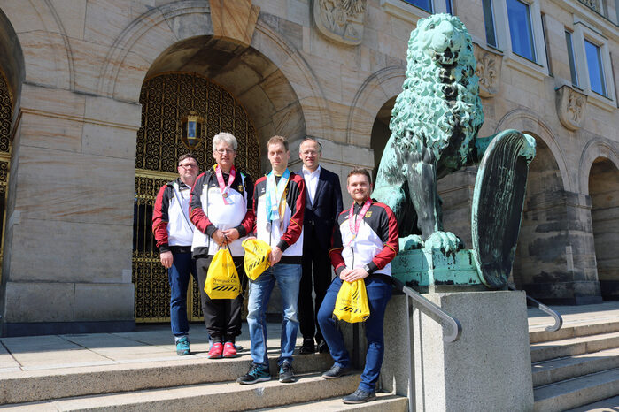 Dr. Lames und vier Sportler vor dem Rathaus-Eingang Goldene Pforte