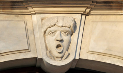 Barockes Fassadendetail, das ein Gesicht in Stein gemeißelt zeigt