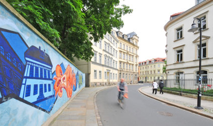 Detailaufnahme eines Graffitis, dahinter Häuserfassaden in der Neustadt