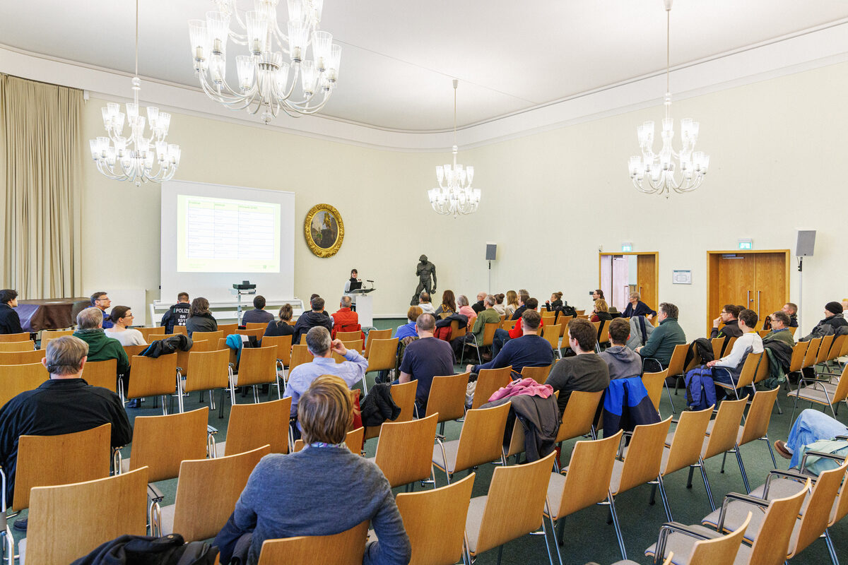 Vielen Menschen sitzen in einem Saal.