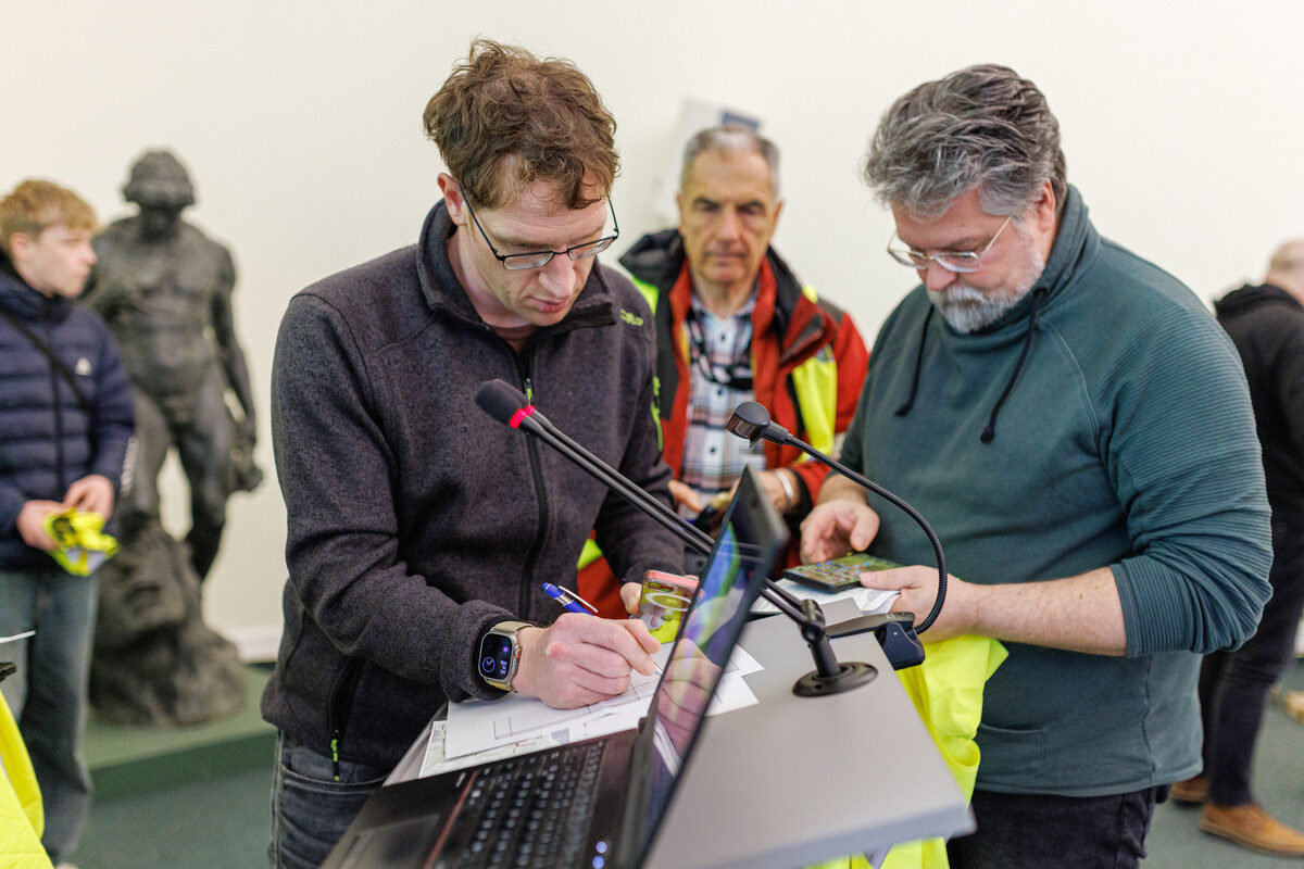 Zwei Menschen stehen an einem Rednerpult und füllen Formulare aus.