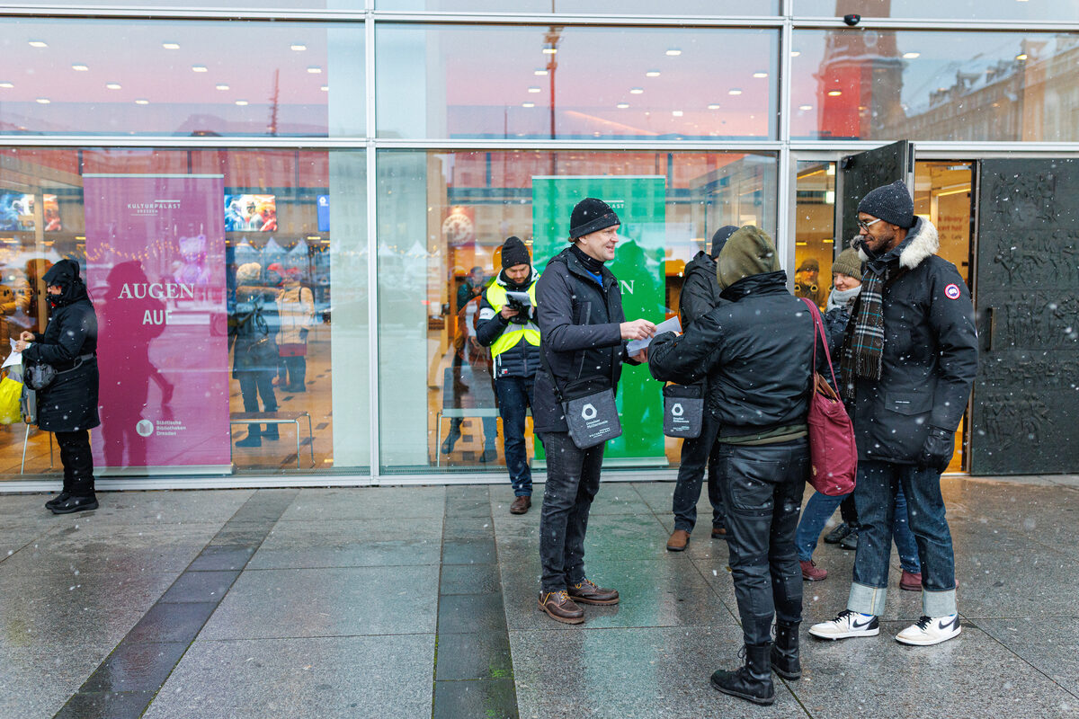 Menschen stehen vor dem Kulturpalast und informieren Passantinnen und Passanten.