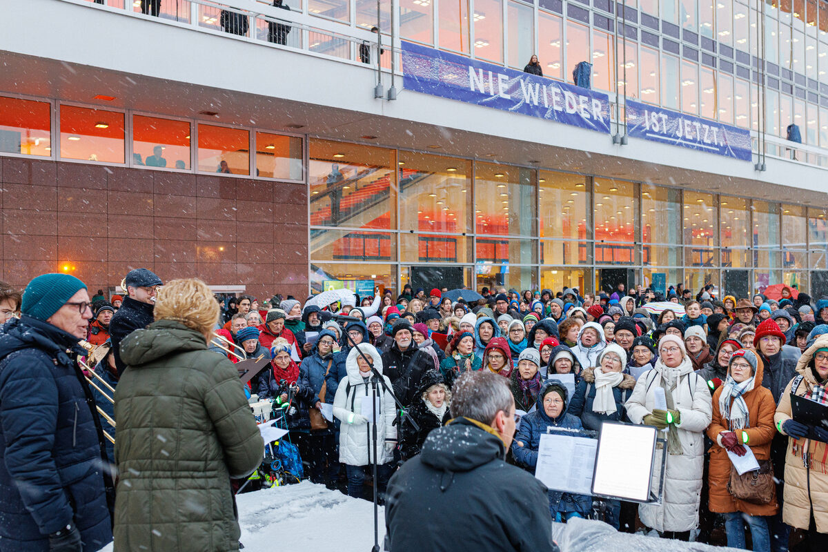 Viele Menschen stehen dicht gedrängt beieinander und singen.