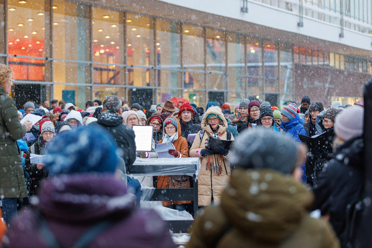 Viele Menschen stehen dicht gedrängt beieinander und singen.