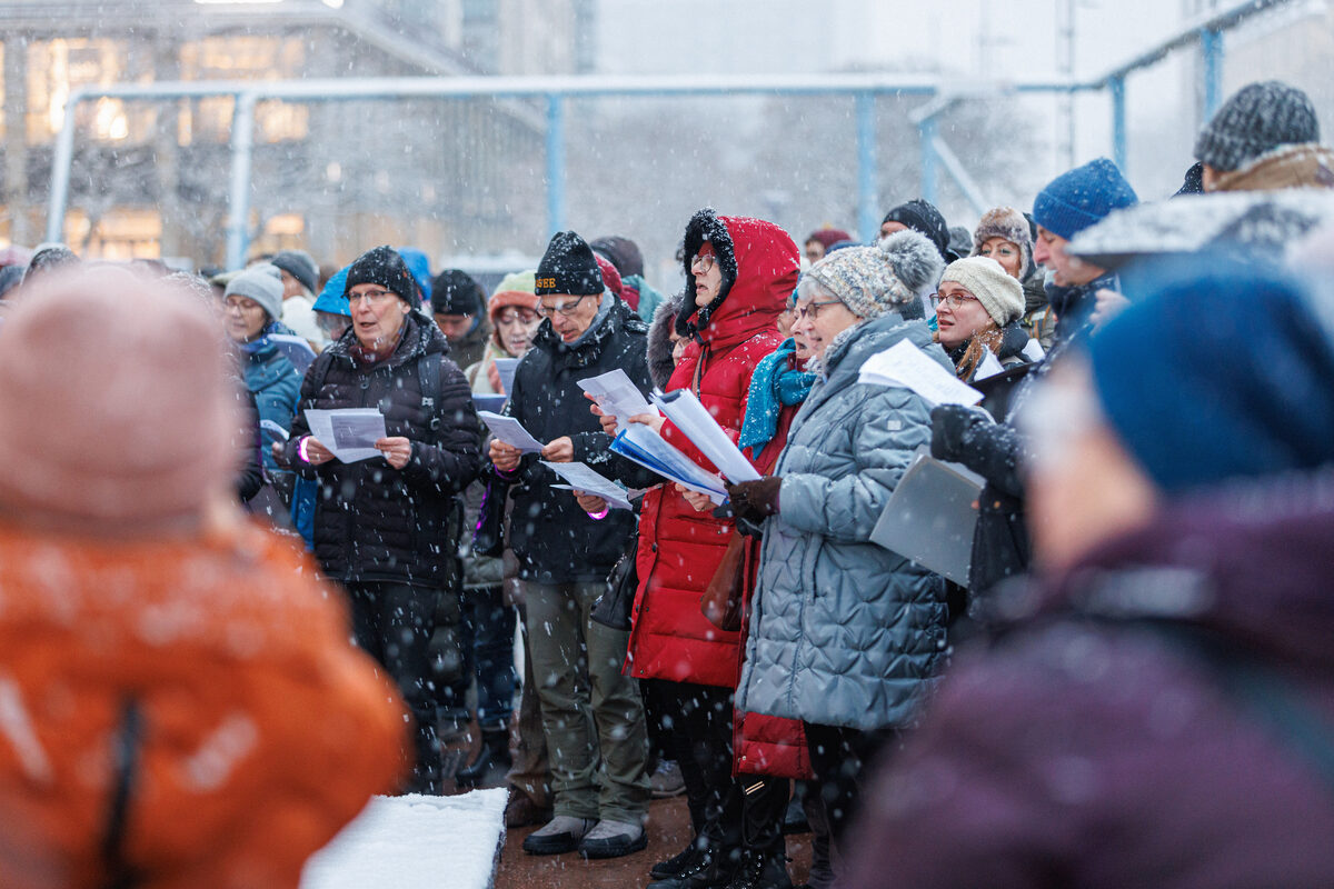 Viele Menschen stehen dicht gedrängt beieinander und singen.