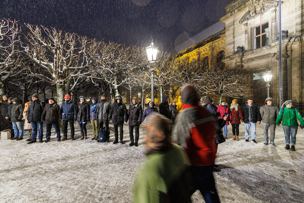 Viele Menschen stehen in einer Kette und halten sich an den Händen