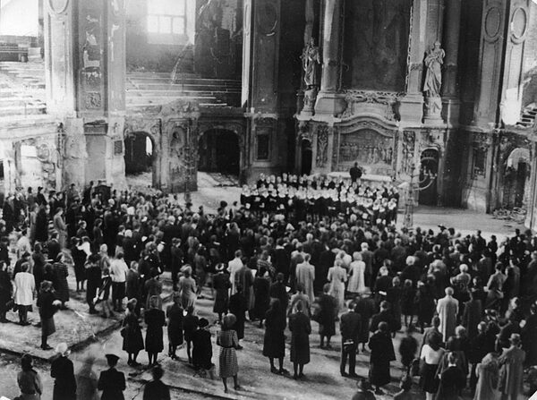 Chor und stehende Zuhörer in der beschädigten Kirche