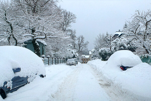 verschneite Straße mit Autos von Schnee bedeckt