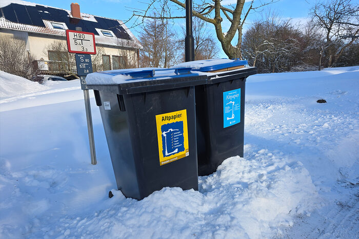Zwei Abfalltonnen für Altpapier im Schnee