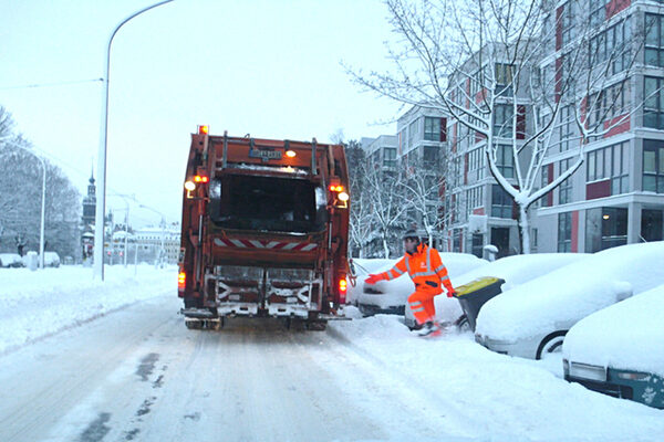 Müllabfuhr im Winter - Müllmann im Schnee der zum Müllauto geht