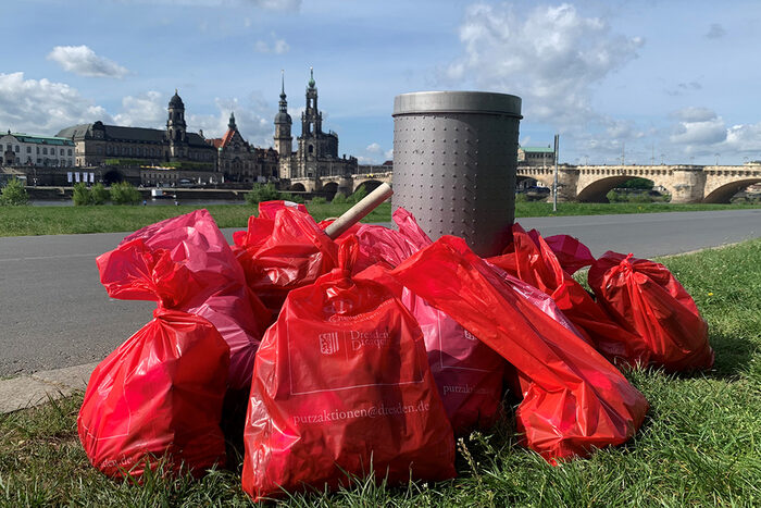 Müllsäcke vor einem Papierkorb im Hintergrund die Altstadt von Dresden