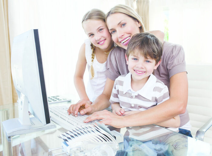 Eine Frau mit zwei Kindern vor einem Computer