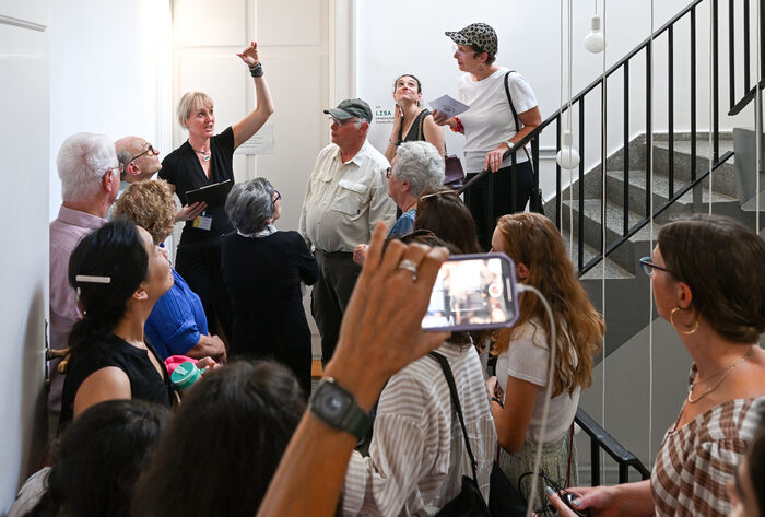 Eine Frau führt eine Gruppe von Besuchende durch das Haus.