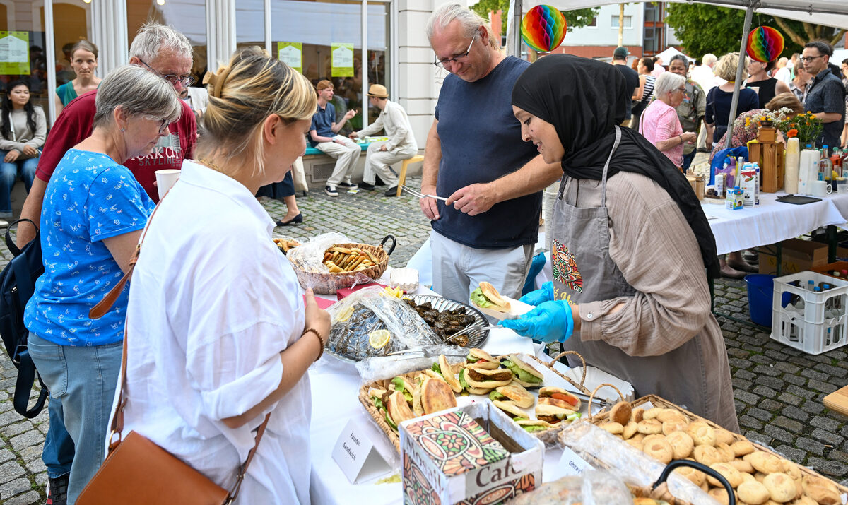 Frau verteilt Essen an Besucherinnen beim Eröffnungsfest.