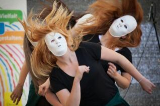 Mehrere junge Tänzerinnen mit weißen Vollmasken