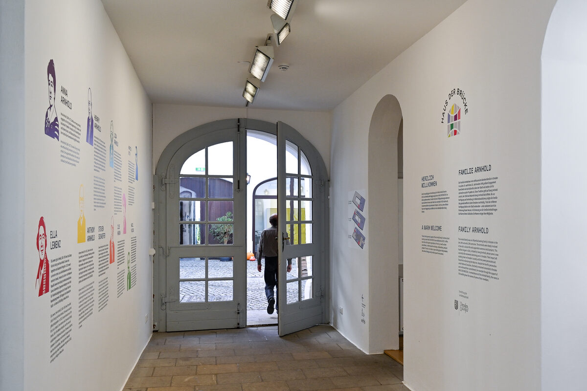 Ein Mann läuft durch den Eingangsbereich, in dem sich die Biografiewand befindet.