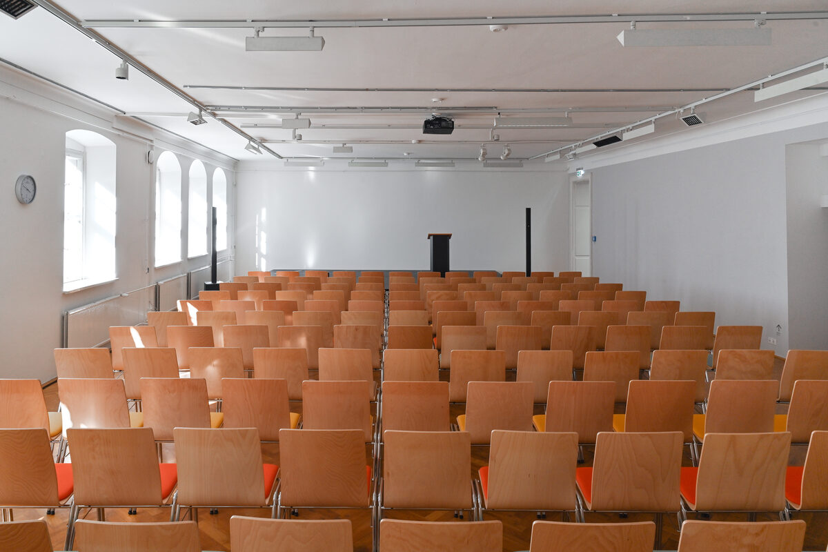 Viele Stühle in Reihen hinter einer kleinen Bühne.