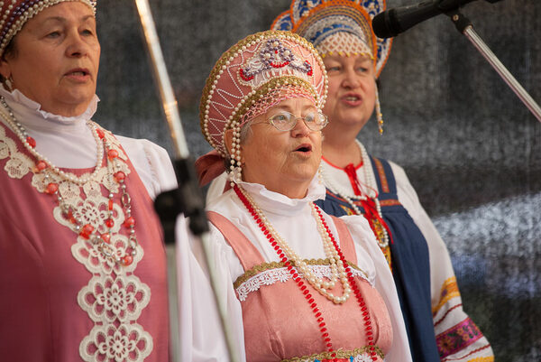 Drei ältere singende Frauen in tradioneller Kleidung