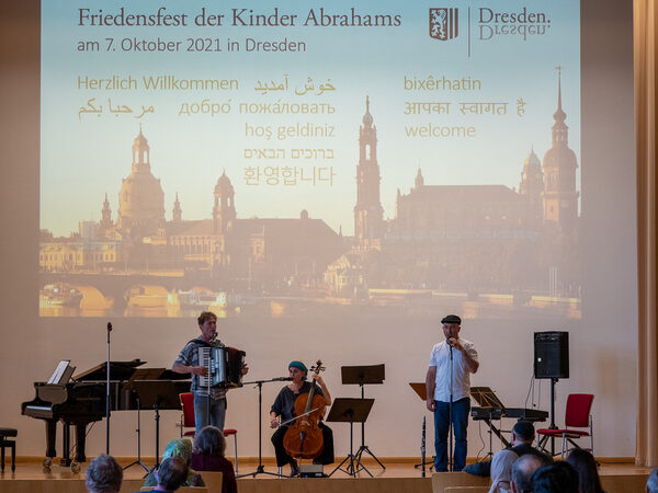 Drei Musiker*innen der Jüdischen Gemeinde auf der Bühne. Davon spielt ein Mann das Akkordeon, eine Frau spielt das Cello und ein weiterer Mann spielt auf der Klarinette.