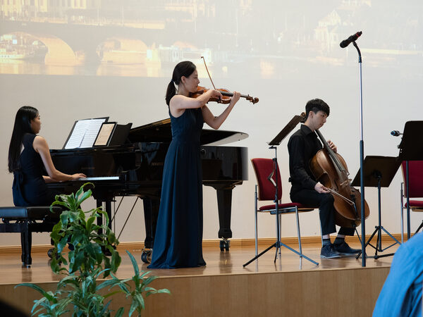 Auf der Bühne musizieren eine Pianistin, eine Geigerin und ein Chellist der Koreanisch Evangelischen Gemeinde.