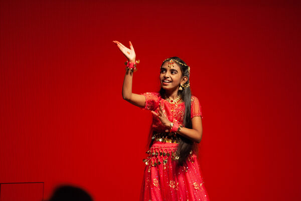 Ein junges Mädchen der Indian Association Dresden tanzt in einem roten Gewand auf der Bühne.