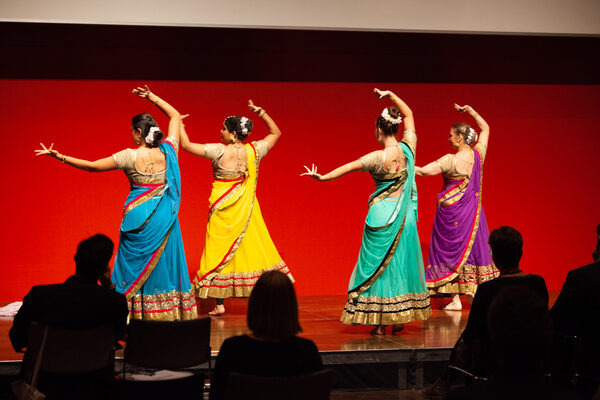 Vier Frauen der Indian Association Dresden tanzen in traditionellen bunten indischen Gewändern auf der Bühne