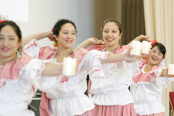 Vier Frauen tanzen in rot-weißen, lateinamerikanischen Roben zu Musik.