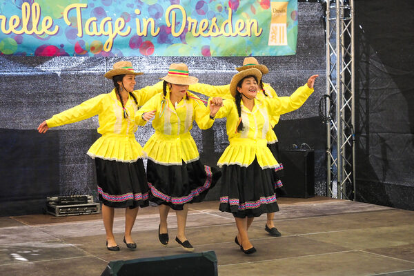 Vier Frauen mit schwarz-gelben Roben tanzen auf der Bühne.