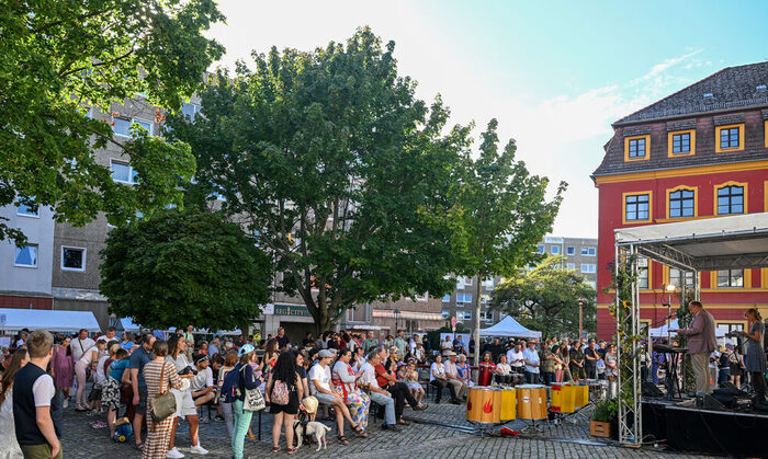 Menschen stehen vor dem HAUS DER BRÜCKE. Dirk Hilbert hält eine Rede.