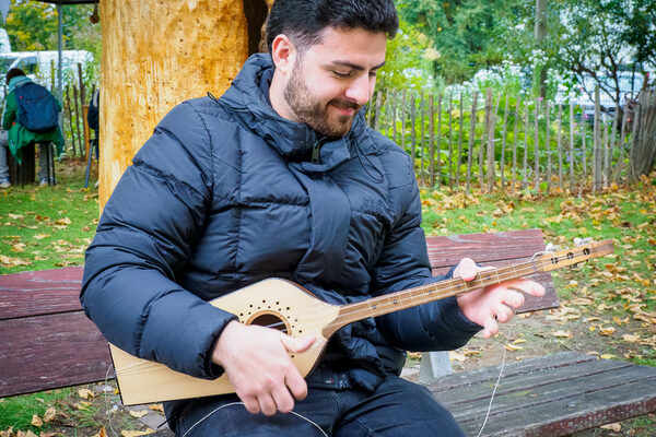 Ein Mann sitzt auf einer Bank mit einer traditionellen georgischen Gitarre