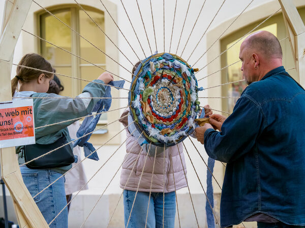 Besucherinnen und Besucher versuchen sich beim Weben