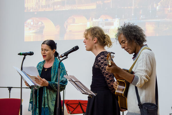 Zwei Sängerinnen und ein Gitarrenspieler sind auf der Bühne beim Friedensfest zu sehen