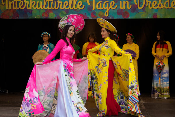 Tänzerinnen in traditioneller, bunter asiatischer Kleider tanzen auf der Bühne