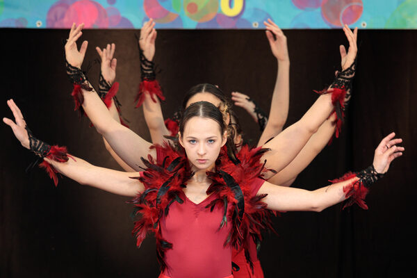 Bühnenprogramm mit Tänzerinnen in roten Kleidern und Federschmuck