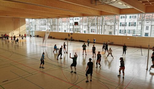 Mannschaften spielen Volleyball in einer Schulsporthalle
