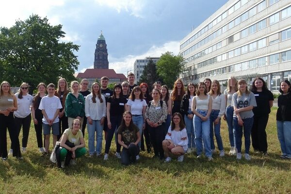 Eine große Gruppe Jugendliche posiert für die Kamera, im Hintergrund der Rathausturm und die Gebäude der Lignerallee Dresden.