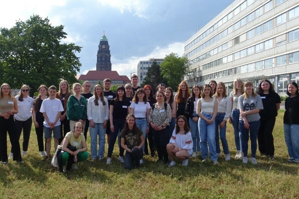 Eine Gruppe Jugendliche posiert für die Kamera, im Hintergrund der Rathausturm und die Gebäude der Lignerallee Dresden.