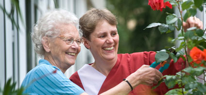 Eine junge Frau hilft einer Seniorin beim Rosenschneiden