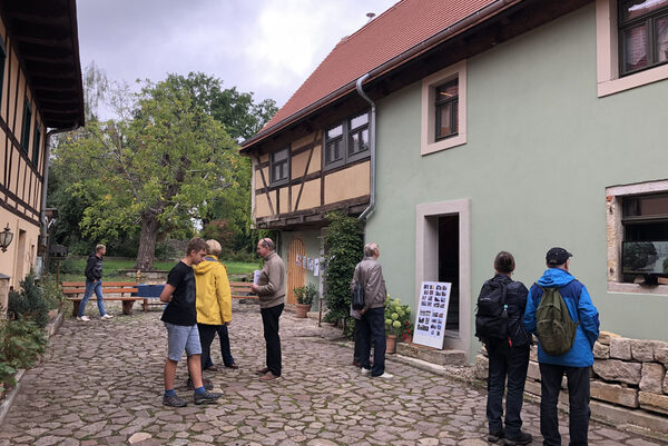 Besucher in einem der sanierten Alttrachauer Höfe: Feldstein-Pflasterung, links und rechts Gebäude teilweise mit Fachwerk