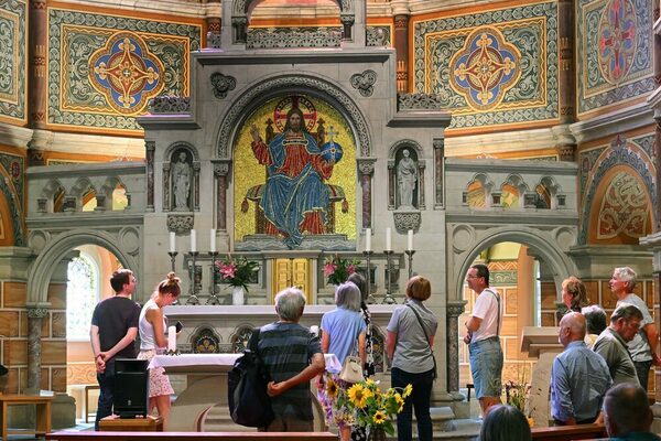 Altar und Chorraum der Garnisonkirche mit großflächigen Mosaiken werden von Besuchern erklärt.