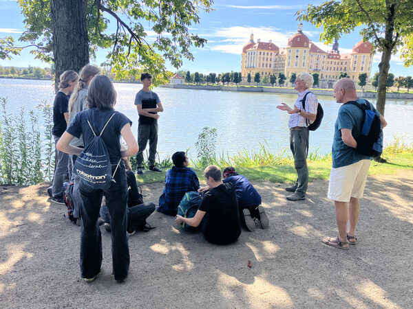 Projektbetreuer und Jugendgruppe am Teich, im Hintergrund Schloss Moritzburg