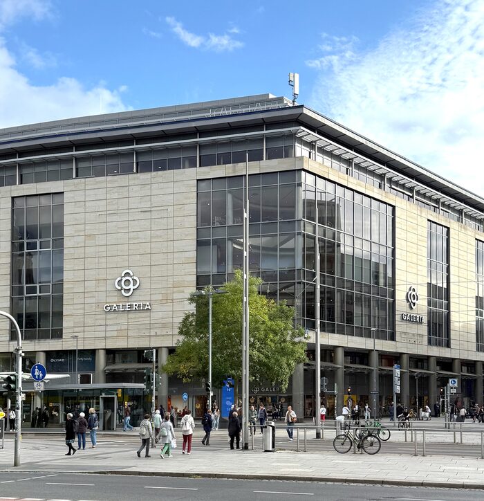 Das Galeriakaufhaus auf der Pragerstraße von außen. Davor laufen Fußgänger und die Sonne scheint.
