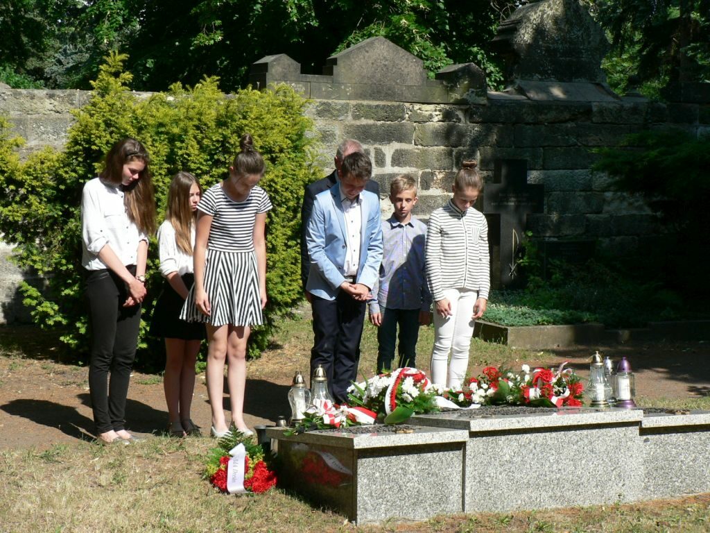 Schülergruppe verneigt sich am Gedenkstein auf dem Friedhof