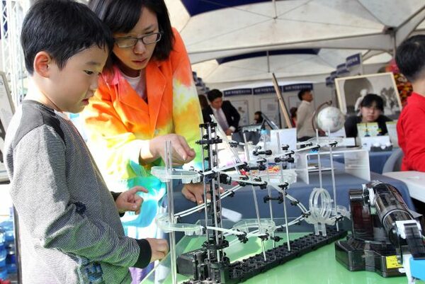 Daejeon Science Festival - eine Frau erklärt einem Kind etwas an einem Gerät